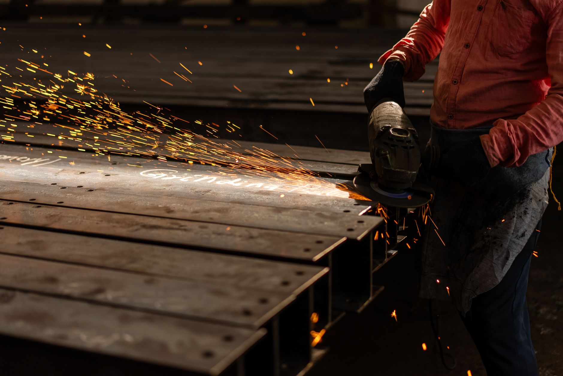industrial worker grinding metal with sparks